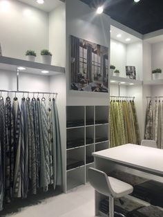 a room filled with lots of shirts and ties on shelves next to a white table