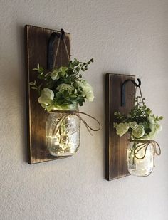 two mason jar wall sconces with flowers in them hanging on the wall next to each other