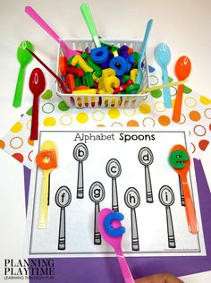 an alphabet spoons game is displayed on a table with colorful plastic utensils