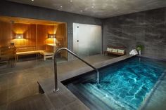 an indoor swimming pool with blue water in the middle and wooden furniture on either side