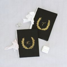 two black wedding guest book with gold monogrammed wreaths and initials on them