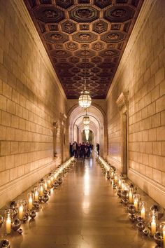 candles are lined up in the middle of a long hallway that leads to an ornate ceiling