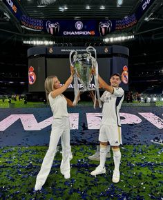 two women in white uniforms holding up a trophy