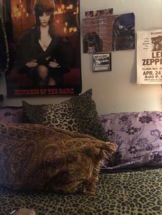 a bed with leopard print pillows and pictures on the wall above it, next to a lamp