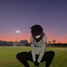 a person sitting on the ground in front of a soccer field at sunset or dawn