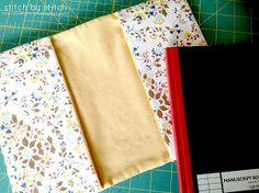 two pieces of fabric sitting on top of a cutting board next to scissors and paper