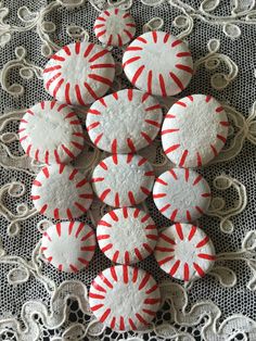 red and white decorated cookies sitting on top of a lace doily covered table cloth