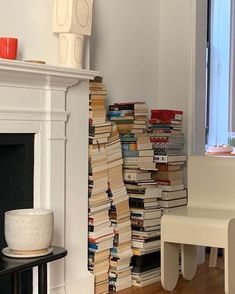 a stack of books sitting next to a fireplace