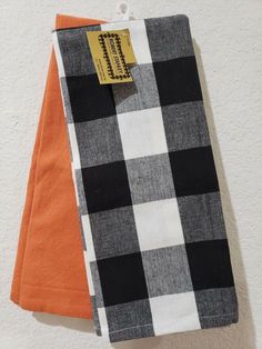 two black and white checkered cloths hanging on a clothes line with an orange tag