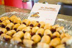 there are many small snacks on the counter top in this display case, including mini pigs in a blanket