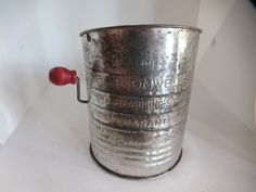 an old metal bucket sitting on top of a white table next to a red push button