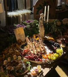 an assortment of fruits and vegetables on display at a market stall with candles in the background