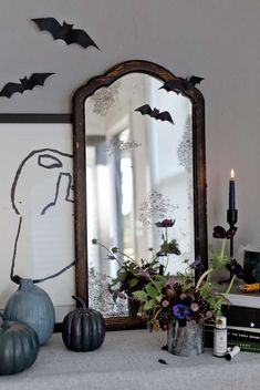 a mirror sitting on top of a mantle next to a vase filled with flowers and bats