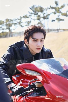 a man sitting on top of a red motorcycle