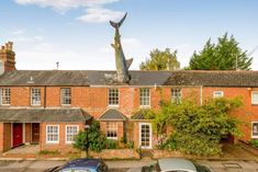 two cars parked in front of a brick building with a shark statue on the roof