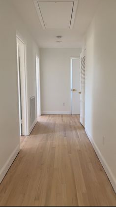 an empty room with hard wood flooring and white walls on either side of the door