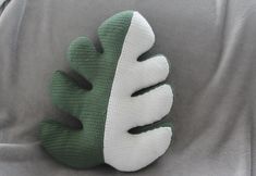 a green and white hand is resting on the back of a gray seat cushion,