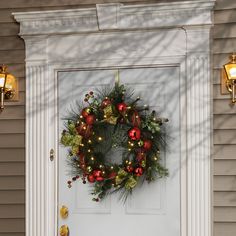 a wreath on the front door of a house with christmas decorations and lights around it