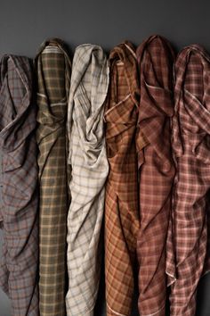 four different colored plaid shirts lined up in a row on a gray surface with one folded over the other