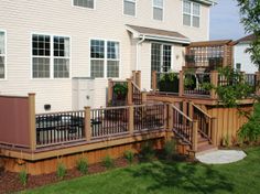 a wooden deck with railings next to a white house