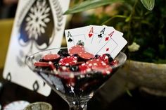 a martini glass filled with red and black diced poker chips sitting on top of a table