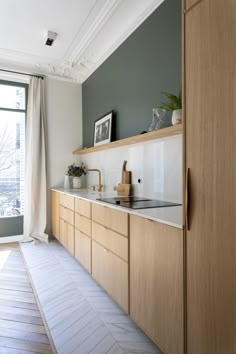 a kitchen with wooden cabinets and white counter tops next to a large window in the background