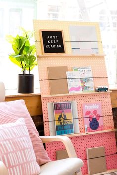 a room with a chair, bookshelf and a potted plant on the window sill