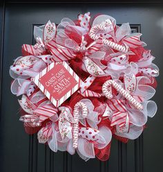 a red and white christmas wreath with candy canes on the front door for someone's house