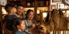 a family looking at a sloth hanging on a wall