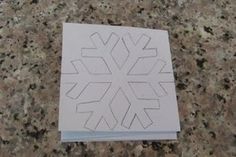 a snowflake cut out on top of a white piece of paper sitting on a counter