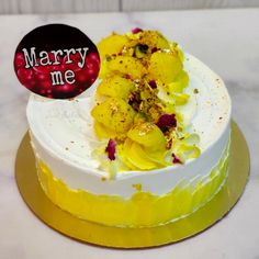 a white cake with yellow frosting and flowers on top that says marry me next to it