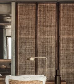 a bed with pillows and a lamp in front of some bamboo screens on the wall