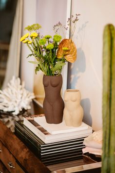 two vases with flowers in them sitting on a table next to a mirror and other items