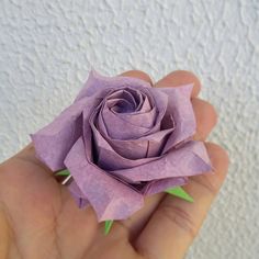 a person is holding a purple paper rose