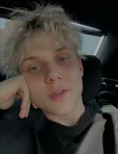 a young man sitting in the back seat of a car