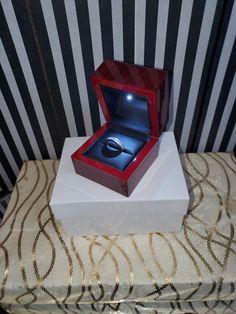 an open ring box sitting on top of a table next to a black and white wall