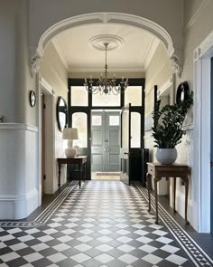 a hallway with checkered flooring and chandelier hanging from the ceiling next to an entry door