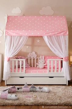 a pink and white baby's room with a canopy bed, stars on the ceiling