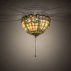 a light fixture with a stained glass shade hanging from it's ceiling in a dark room