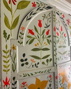 an ornate painted wall with flowers and leaves on the outside, behind it is a door