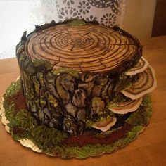 a cake made to look like a tree stump with mushrooms and leaves around it on a wooden table