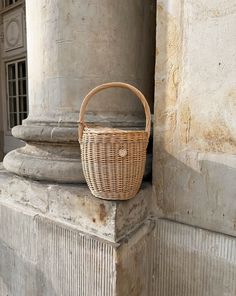 a wicker basket sitting on top of a stone pillar in front of a building