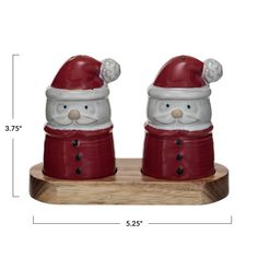 two red and white santa claus salt and pepper shakers on a wooden stand with measurements