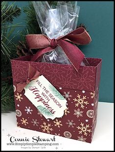 a bag with a tag on it sitting next to a christmas tree and pine cones