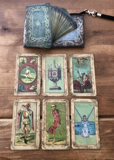 six tarot cards are laid out on a wooden table with an open wallet and keychain