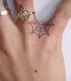 a woman's hand with a spider web tattoo on it