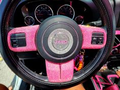 the interior of a pink and black car with steering wheel cover covered in swarong