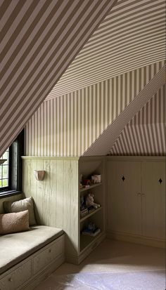 an attic bedroom with striped walls and built - in bookshelves is seen on the phone