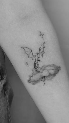 a black and white photo of a person's arm with a bat tattoo on it