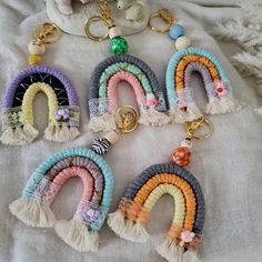 six key chains with tassels and beads hanging from them on a white cloth